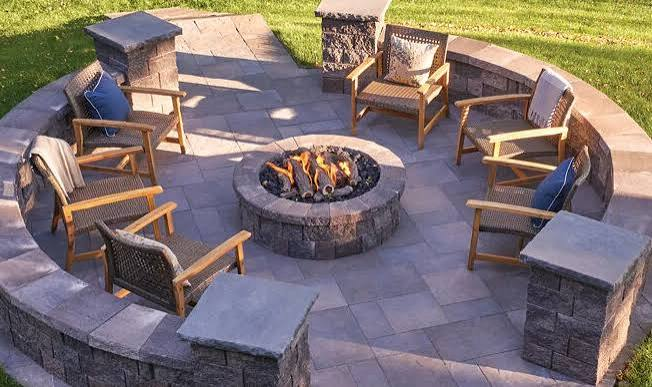 Round stone fire pit with chairs and a surrounding patio wall