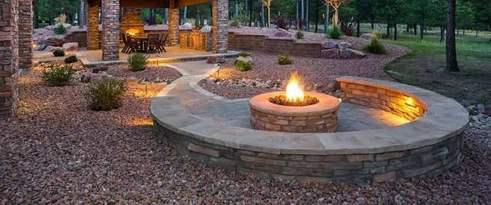 Stone fire pit and curved seating wall in a landscaped backyard